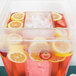 A clear Cal-Mil beverage dispenser ice chamber filled with pink liquid, strawberries, lemons, and oranges.