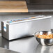 An Edlund stainless steel film and foil dispenser on a stainless steel counter.