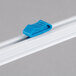 A blue plastic Edlund film dispenser blade clip on a white rail.
