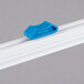 A blue plastic clip on a white piece of plastic.