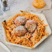 A EcoChoice palm leaf plate with a plate of spaghetti and meatballs and bread on a table.