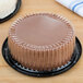 A chocolate cake in a D&W Fine Pack plastic container with a clear dome lid.