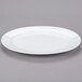 A Libbey Aluma White Porcelain Platter with a rim on a gray surface.