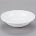 A Libbey white porcelain fruit bowl with a small rim on a gray surface.