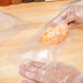 A person in plastic gloves using an ARY VacMaster plastic bag to vacuum package a piece of food.