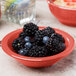A Libbey Cantina porcelain fruit bowl filled with blackberries and blueberries on a table.