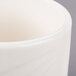 A close up of a Libbey ivory porcelain bouillon cup with a white rim.