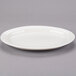 An ivory Libbey oval medium rim porcelain platter on a gray surface.