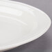 A close up of a Libbey ivory porcelain oval platter with a rim on a gray surface.