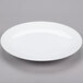 A Libbey aluma white porcelain coupe plate with a rim on a gray surface.