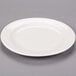 A Libbey ivory porcelain plate with a rim on a gray surface.