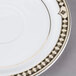 A close-up of a white Syracuse China Baroque saucer with gold details.