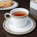 A Syracuse China stackable saucer with a cup of tea on it.