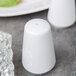 A white Libbey porcelain salt shaker on a table.