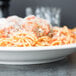 A Libbey ivory porcelain entree bowl filled with spaghetti and meatballs.
