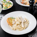 A white porcelain Libbey Reflections pasta bowl filled with pasta and salad.