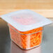 A translucent plastic Cambro lid on a container of food with carrots.