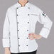 A woman wearing a white Mercer Culinary chef coat with black piping.