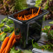 A Carlisle black plastic food pan filled with carrots and lettuce.