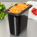 A Carlisle black polycarbonate food pan with shredded carrots on it.
