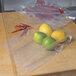 A plastic bag filled with lemons, limes, and red peppers on a table.
