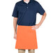 A man wearing an orange Intedge waist apron over a blue shirt and black pants.