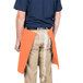 A man wearing an orange Intedge waist apron with a pocket.