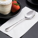 A Libbey Aspire stainless steel dessert spoon on a plate of cake.