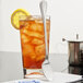 A glass of iced tea with a Libbey stainless steel iced tea spoon and a lemon slice.