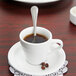 A cup of coffee with a Libbey stainless steel demitasse spoon on a saucer.