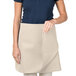 A woman wearing a beige Intedge waist apron with pockets.