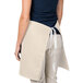 A woman wearing a beige Intedge waist apron with a pocket.