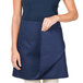 A woman wearing a navy blue Intedge waist apron with pockets.