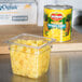 A container of Del Monte pineapple chunks on a counter next to a Del Monte #10 can of pineapple chunks.