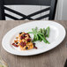 A 10 Strawberry Street Bistro white porcelain oval platter with fish and green beans on a table.