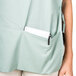 A woman wearing a sea green cobbler apron with pockets.