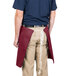 A man wearing a burgundy Intedge waist apron.