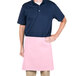 A man wearing a blue shirt and a pink Intedge waist apron standing with his hands on his hips.