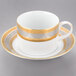 A white porcelain teacup and saucer with a gold border.