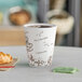 A Choice double wall paper hot cup with a bean print filled with coffee on a table with croissants.