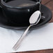 A black cup and saucer with a Libbey stainless steel demitasse spoon on a white napkin.
