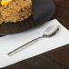 A World Tableware Zephyr stainless steel teaspoon on a plate with rice and lemons.