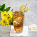 A glass of iced tea with a Libbey Geneva stainless steel iced tea spoon in it, ice, and lemon slices.