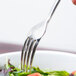 A Libbey stainless steel salad fork over a salad.