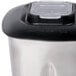 A Waring stainless steel blender jar with a clear lid on a counter.