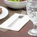 A Libbey stainless steel dinner fork on a napkin next to a bowl of salad.