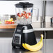 A Waring bar blender with a black container and a banana inside.