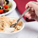 A hand holding a Libbey stainless steel dessert spoon over a bowl of ice cream.