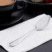 A Reserve by Libbey stainless steel teaspoon on a napkin next to a cup of coffee.