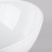 A close up of a white Tablecraft Sierra large round melamine bowl with a curved edge.